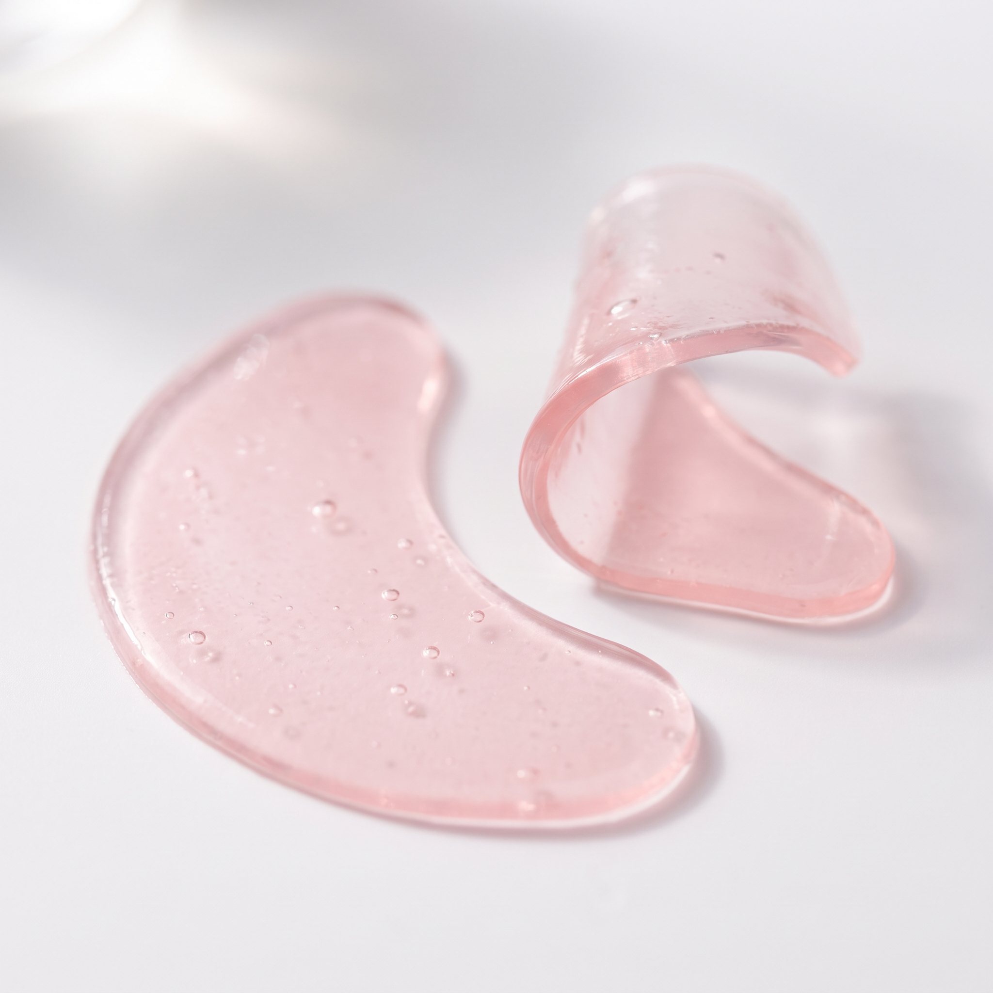 Two translucent pink hydrogel eye patches showing gel texture and thickness